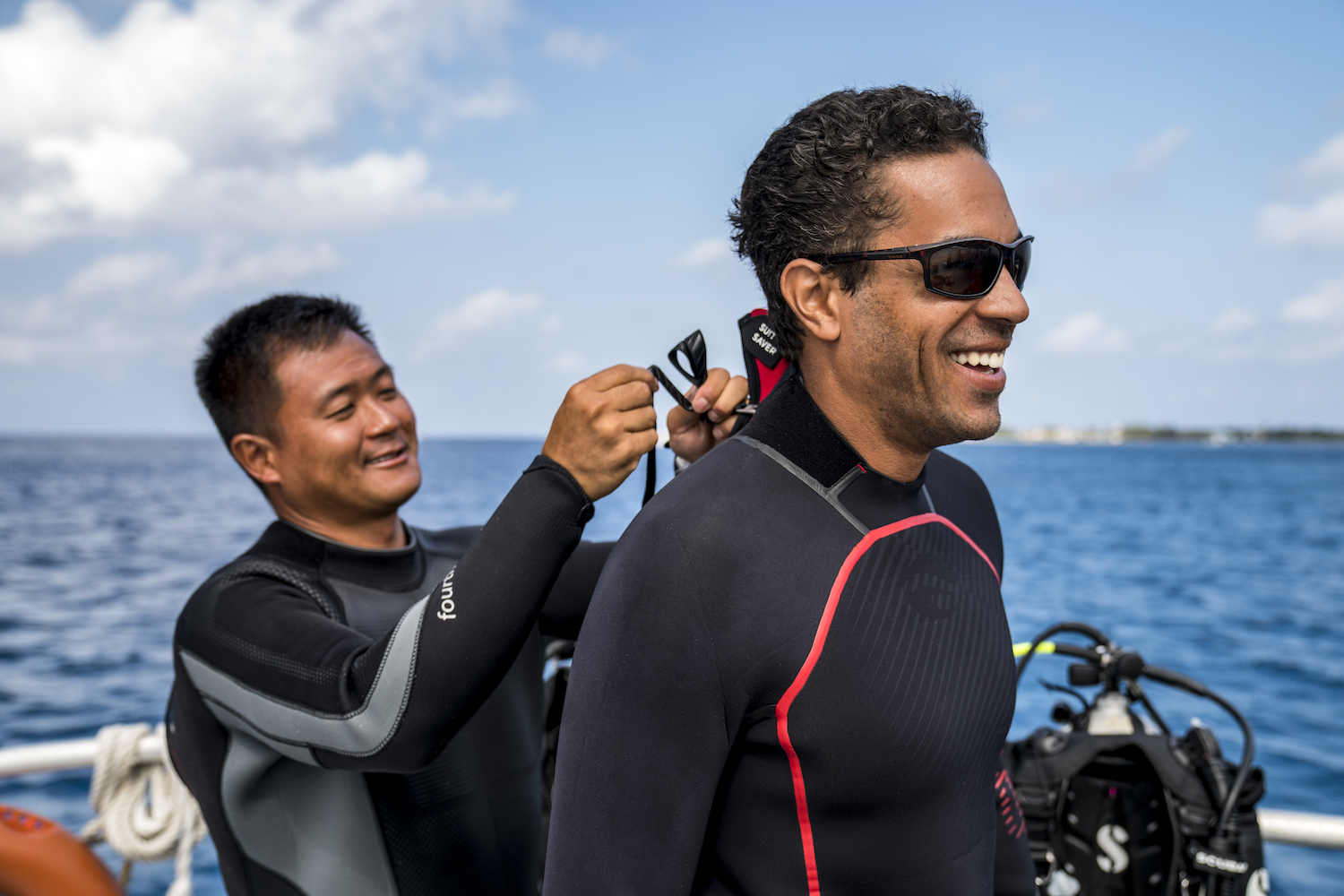 Zipping up a wetsuit A scuba diver helping his buddy put on his wetsuit, a useful distraction for a way how to get over anxiety when scuba diving