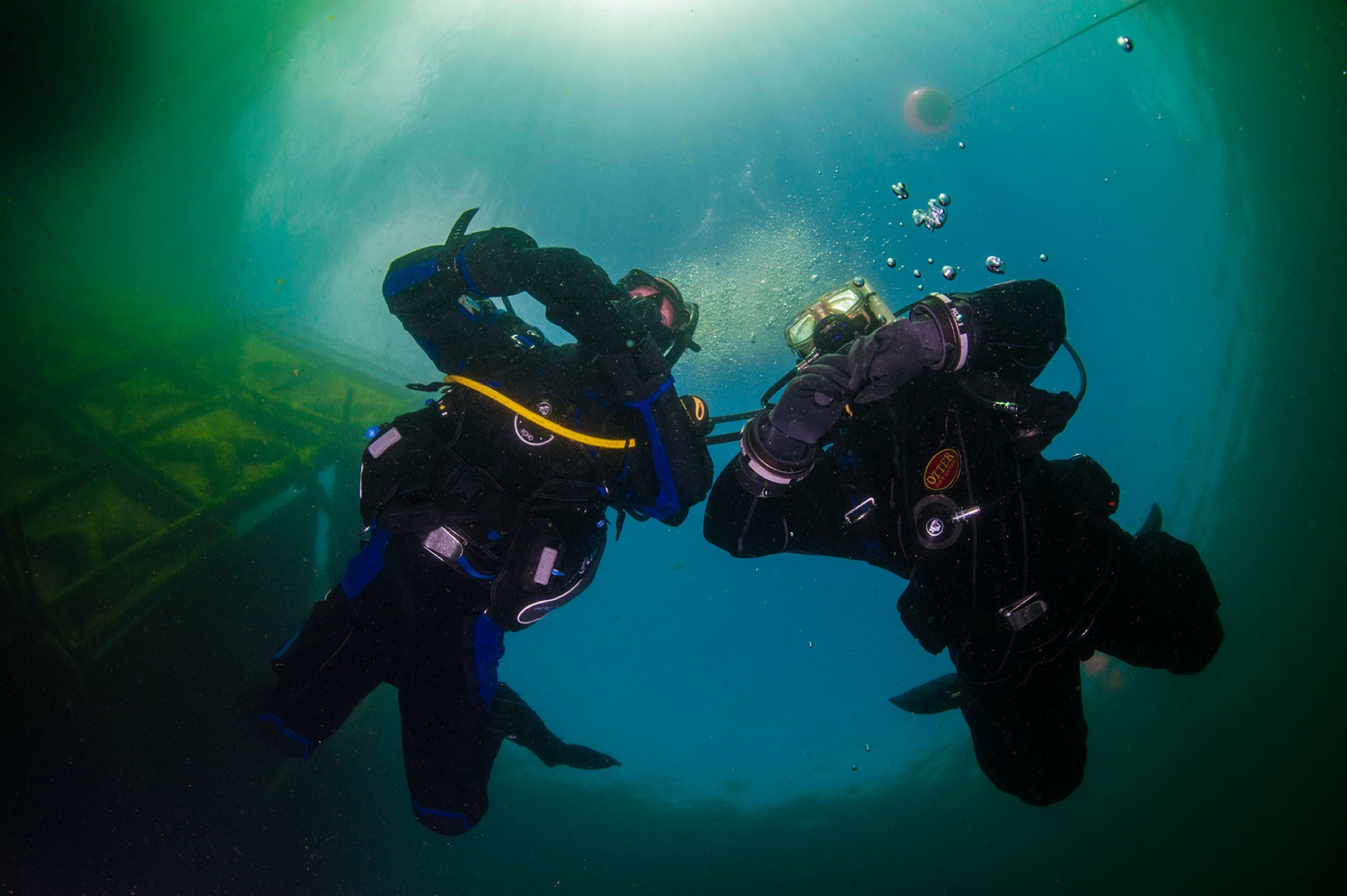 A safe scuba ascent Two scuba divers in drysuits are ascending safely and slowly to the surface as they know rapid ascents can cause diving bends