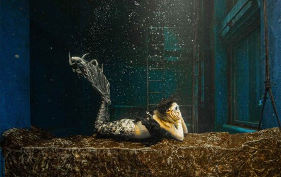 mermaid posing with her chin resting in her hands.
