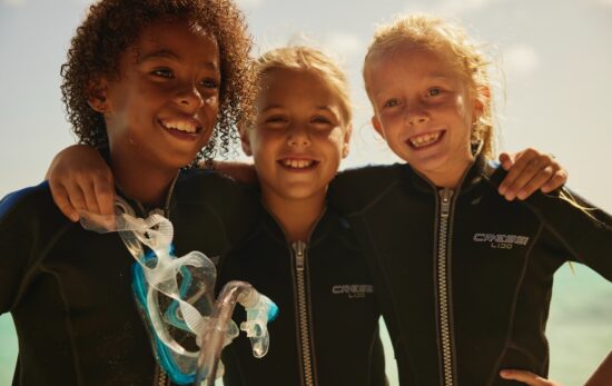 three young divers hug and smile for the camera